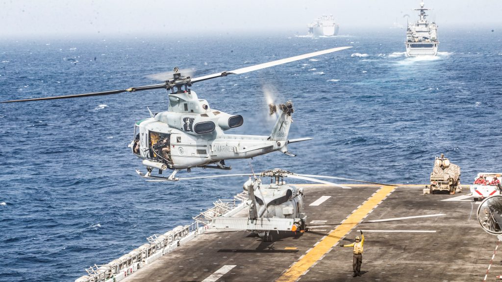 تحلق طائرة هليكوبتر تابعة لقوات المارينز الأمريكية UH-1Y Venom من على سطح رحلة سفينة هجومية برمائية تابعة للبحرية الأمريكية USS Boxer ، بالقرب من نظام طائرة مضادة للطائرات بدون طيار ، ونظام مدمج على ضوء نظام الطيران البحري المتكامل (LMADIS) متوقفة عند القوس ، أثناء عبورها عبر مضيق هرمز