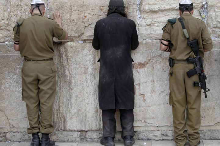 جنود إسرائيليون ورجل يهودي أرثوذكسي متطرف يصلون على الحائط الغربي في المدينة القديمة بالقدس/ أ ف ب