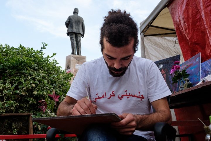 محمود الخاش ، متظاهر مع والد سوري وأم لبنانية يرسم خارج خيمته (MEE / ريتا قبلان) )