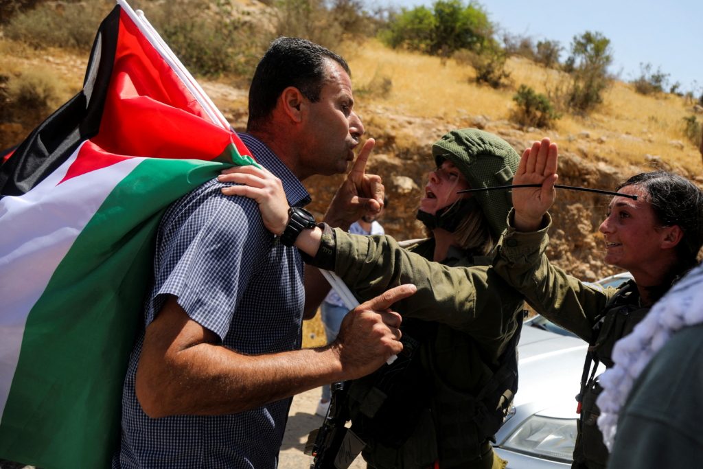 جندية إسرائيلية تحاول انتزاع علم فلسطين من متظاهر فلسطيني بالأراضي المحتلة/ ٧ يونيو ٢٠٢٢ - رويترز