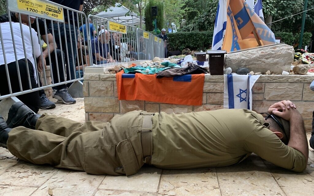 جندي إسرائيلي يختبئ ويداه فوق رأسه بعد سماع صفارات الإنذار أثناء جنازة الضابط نتانيل يونغ الذي قتل في غلاف غزة/ Times of Israel